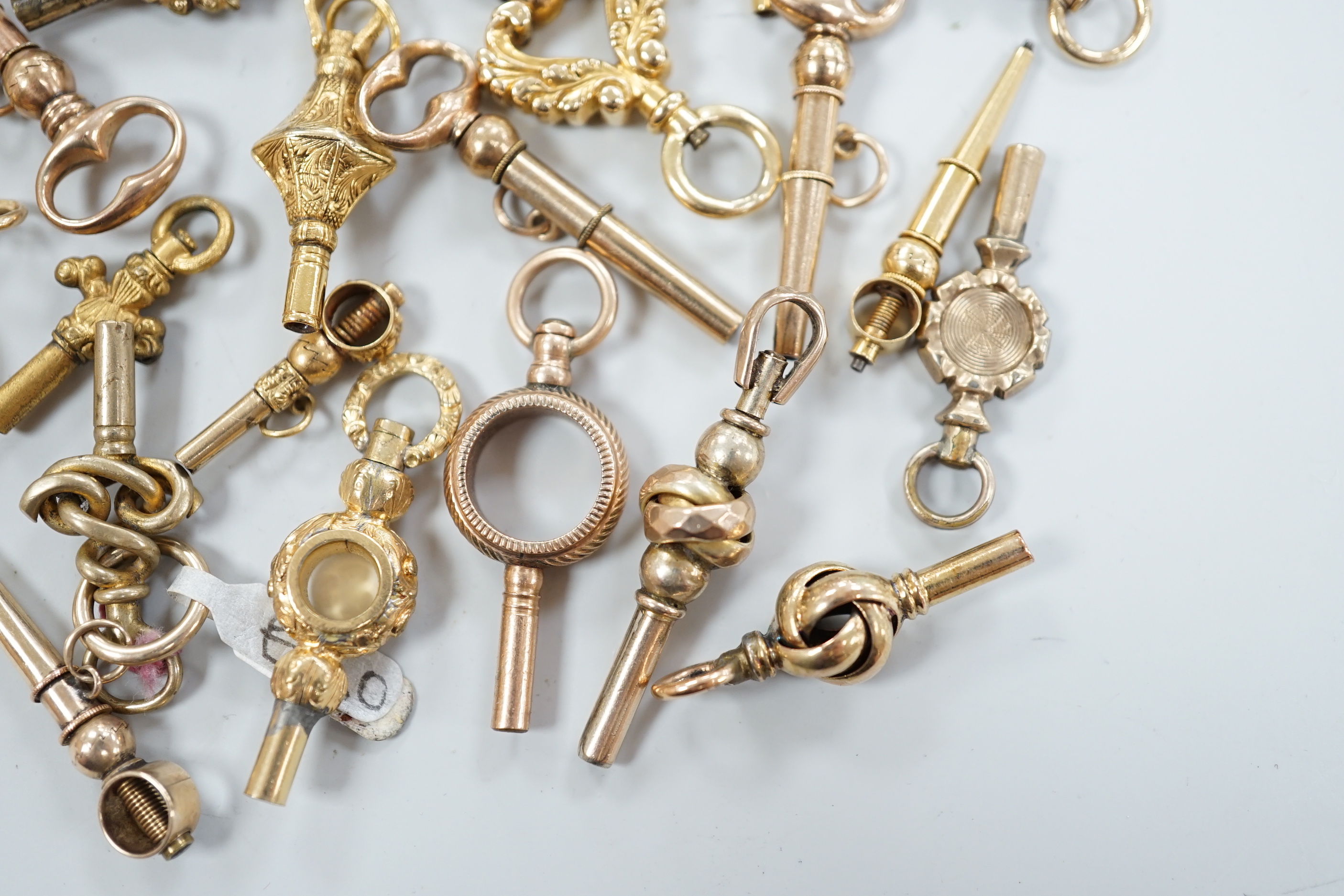 Twenty assorted mainly 19th century yellow metal small watch keys, including trade insignia, bloodstone set and keys to be turned in one direction, largest 37mm, together with a 19th century yellow metal overlaid and aga